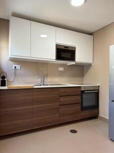 a kitchen with white cabinets and a sink and a microwave at House Real Companhia in Vila Nova de Gaia