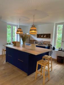 a kitchen with a large blue island with two stools at maison 8 pers avec piscine en pleine nature in Ambenay