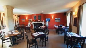 a restaurant with tables and chairs and a fireplace at Hôtel Saint Laurans in Aurignac