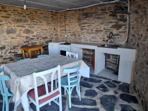 eine Küche mit einem Tisch und Stühlen sowie einem Kamin in der Unterkunft Casiña do Cereixeiro Roblido in Roblido