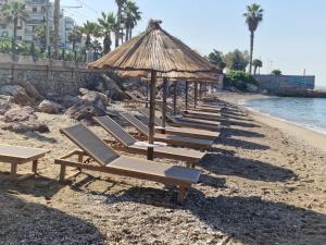 a row of lounge chairs and an umbrella on a beach at Coral Hotel Athens in Athens