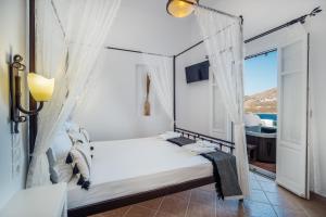 1 dormitorio con 1 cama, ventana y bañera en Astrio Suites en Livadi