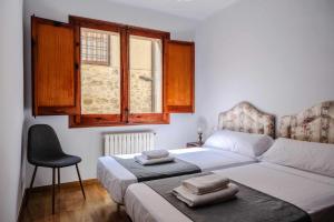 1 dormitorio con 1 cama, 1 silla y 1 ventana en Can Severí casa con historia en Besalú en Besalú