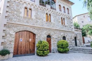 a stone house with two wooden doors and bushes at Can Severí casa con historia en Besalú in Besalú