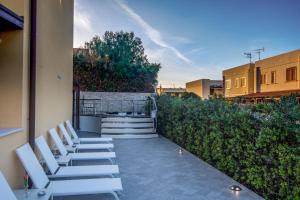 a row of white chairs sitting on a patio at B&B Aloe Comfort Rooms in San Vito lo Capo