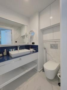 a white bathroom with a toilet and a sink at Apartments Black Sea Resort in Batumi