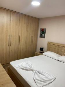 um quarto com uma cama branca e armários de madeira em Lovely one bedroom flat in Durres em Durrës