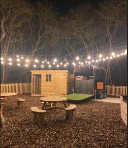 a picnic table in front of a trailer with lights at Cliff Stud Retreat - Luxury lodges and cosy cottages in Helmsley