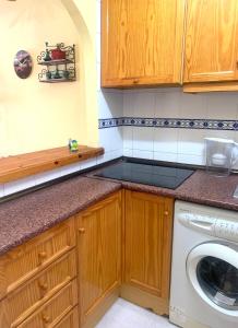 a kitchen with wooden cabinets and a washing machine at ApartalMar in Torrevieja