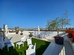 a patio with white chairs and a lawn with plants at Hotel Spazio Residenza in Pescara