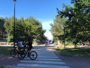 two people riding bikes in a crosswalk in a park at Neptun Park- Apartament Elegance in Gdańsk