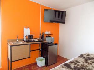 a kitchen with an orange wall with a sink and a microwave at Urban Hotel in Guatemala