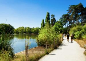 dos personas caminando por un camino junto a un lago en L'Escale aux portes de Paris, en Charenton-le-Pont
