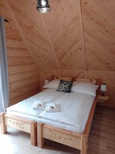 ein Schlafzimmer mit einem Bett in einem Holzzimmer in der Unterkunft Domek Na Góralską Mode in Suche