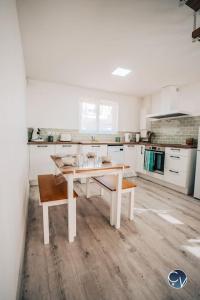 una cocina blanca con una mesa en el medio. en Maison rénovée à 500 m du centre du village, en Goudargues