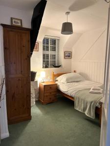 Schlafzimmer mit einem Bett und einem Holzschrank in der Unterkunft Shilla Mill - Just off the Beach in Polzeath