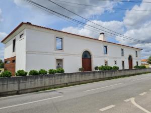 un bâtiment blanc sur le côté d'une route dans l'établissement Quinta das Donas, à Anadia