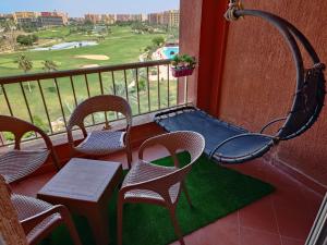 une terrasse couverte avec des chaises et une balançoire sur un balcon dans l'établissement Chalet in Golf Porto Marina golf & pool View Egyptian only, à El Alamein