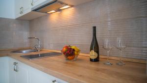 a kitchen counter with a bottle of wine and two wine glasses at Apartments Edera in Tivat
