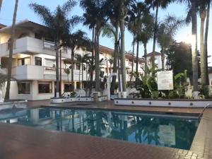 une piscine en face d'un bâtiment avec des palmiers dans l'établissement Hotel Paraiso Las Palmas, à Ensenada