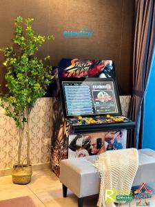a pinball machine in a room with a chair at Atlantis Residences Melaka by HeyStay Management in Melaka