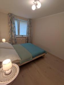 a bedroom with a bed and a table with a lamp at Apartament Natura in Mrągowo