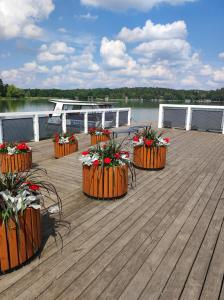 una terraza de madera con macetas de flores en un barco en Apartament Natura en Mrągowo
