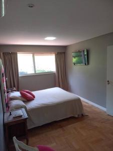 a bedroom with a white bed and a window at Casa amplia - Pileta y parque in Bella Vista