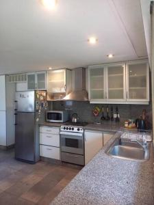 eine Küche mit Küchengeräten aus Edelstahl und einer Spüle in der Unterkunft Casa amplia - Pileta y parque in Bella Vista