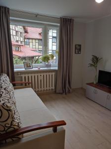 a living room with a couch and a large window at Apartament Natura in Mrągowo
