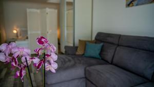 a vase with purple flowers in front of a couch at Apartments Edera in Tivat