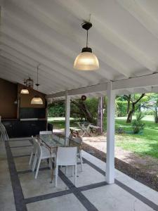 eine Terrasse mit einem Glastisch und weißen Stühlen in der Unterkunft Casa amplia - Pileta y parque in Bella Vista