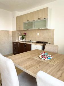 a kitchen with a wooden table with white chairs at Lulu Garden in Ulcinj