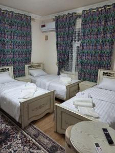 een kamer met drie bedden en een tafel erin bij Qozi Hotel in Samarkand