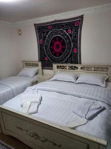 een slaapkamer met 2 bedden en een wandtapijt bij Qozi Hotel in Samarkand