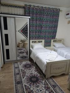 een slaapkamer met 2 bedden en een grote spiegel bij Qozi Hotel in Samarkand