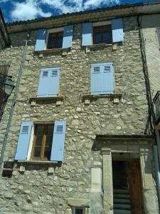 un vieux bâtiment en pierre avec des fenêtres bleues à volets dans l'établissement Villa des Lucioles, à Annot