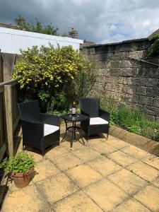 a patio with two chairs and a table with a bottle of wine at Tipsy Cottage Charming 2 bedroom home. in Burley in Wharfedale