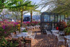 un patio con mesas blancas, sillas y flores en Hotel Presidente, en San José