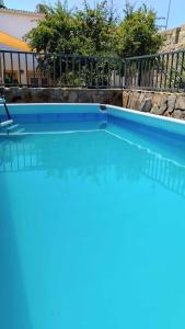 uma piscina com água azul em frente a uma cerca em Casa Rural Los Mayorales em Esparragalejo