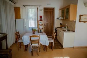 a kitchen with a table with chairs and a refrigerator at Traditional Architecture Seafront Stone House in 25000sqm Olive Grove - C in Alyfantá