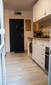 une cuisine avec des placards blancs et une porte noire dans l'établissement Apartament Zeuss Neptun, à Legian