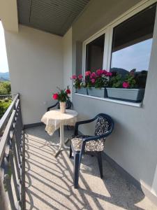 uma varanda com uma cadeira, uma mesa e uma janela em Apartman Mir em Visoko