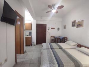 a bedroom with two beds and a flat screen tv at Peristerianos apartments in Nea Skioni