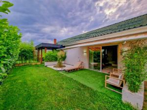 a backyard with a green lawn and two benches at Bambuus Garden & Spa in Drăgăşani