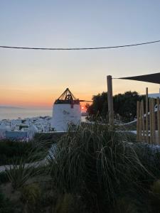 a view of a sunset over a city with a lighthouse at THE VIEW OF MYKONOS in Mýkonos City