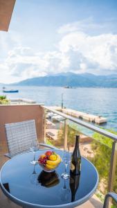 a table with a bowl of fruit and a bottle of wine at Apartments Edera in Tivat