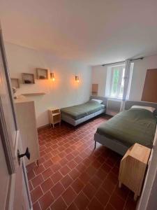 een slaapkamer met 2 bedden en een rode tegelvloer bij Maison de village le Barroux *Clim* in Le Barroux