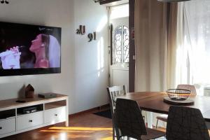a living room with a table and a television on a wall at MAISON DE VACANCES aU 91 in Ardres