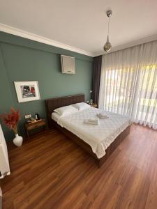 a bedroom with a large bed and a green wall at HESTİA ILICA in Cesme